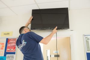 Handyman fitting a TV to a wall