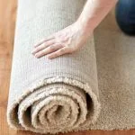 how-to-get-rid-of-new-carpet-smell person rolling a new carpet