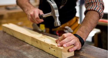 Handyman knocking a nail into piece of wood