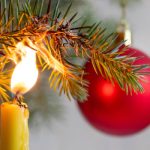 A candle starting to burn a Christmas tree branch