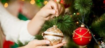 woman putting a bauble on a christmas tree