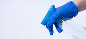 hand in blue glove spraying disinfectant