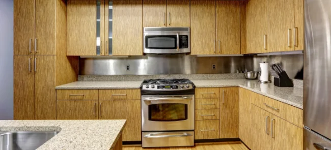 A modern looking kitchen with a steel splashback, oven and a microwave
