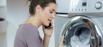 Woman in front of washing machine calling a technician