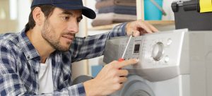 Appliance repair engineer fixing a faulty washing machine