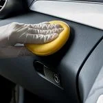 A person's hand removing scratches from car interior.