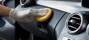 A person's hand removing scratches from car interior.