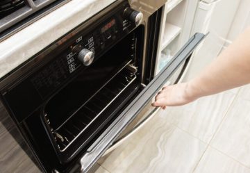A woman opens the door of a modern catalytic oven