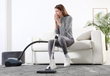 Woman sneezing while cleaning the carpet