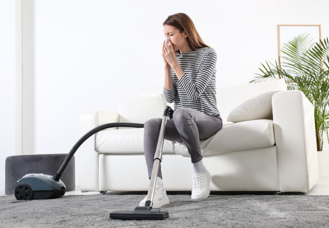 Woman sneezing while cleaning the carpet