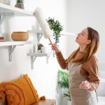 Woman dusting shelves in her living room
