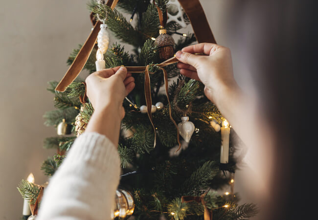 Woman decorating a Christmas tree with ribbons
