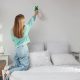 Woman cleaning mould in bedroom on wall