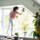 Woman manually washes the window of the house with rag cleaner and mop on windowsill