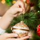 woman putting a bauble on a christmas tree