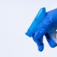 hand in blue glove spraying disinfectant