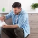 Handsome man taking dirty dishes out of dishwasher