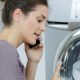 Woman in front of washing machine calling a technician