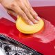 A mans hand with a watch polishing red car